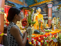 A lady is offering a lotus flower to an idol of Lord Buddha at a monastery on the occasion of Buddha Purnima in Kolkata, India, on May 23, 2...