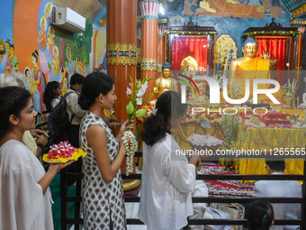 People are offering a lotus flower to an idol of Lord Buddha at a monastery on the occasion of Buddha Purnima in Kolkata, India, on May 23,...