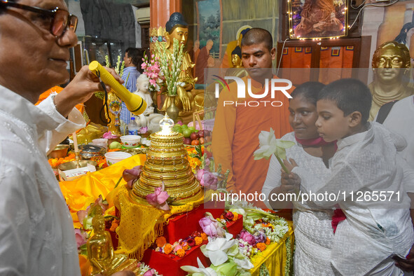 A mother and child are offering prayers to a relic of Gautam Buddha, which contains the remains of Buddha, at a monastery in Kolkata, India,...