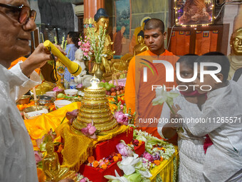 A mother and child are offering prayers to a relic of Gautam Buddha, which contains the remains of Buddha, at a monastery in Kolkata, India,...