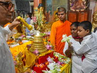 A mother and child are offering prayers to a relic of Gautam Buddha, which contains the remains of Buddha, at a monastery in Kolkata, India,...