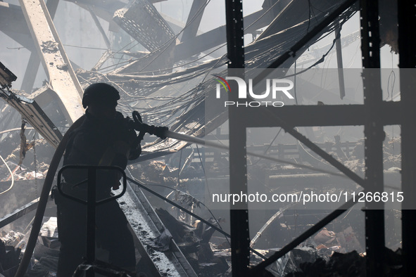 A firefighter is pouring water during a response effort to a Russian S-300 missile strike on a printing company in Kharkiv, Ukraine, on May...