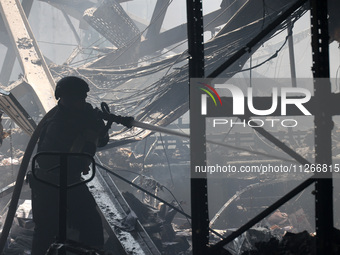 A firefighter is pouring water during a response effort to a Russian S-300 missile strike on a printing company in Kharkiv, Ukraine, on May...