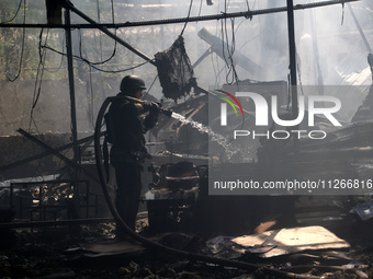 A firefighter is pouring water during a response effort to a Russian S-300 missile strike on a printing company in Kharkiv, Ukraine, on May...