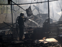 A firefighter is pouring water during a response effort to a Russian S-300 missile strike on a printing company in Kharkiv, Ukraine, on May...