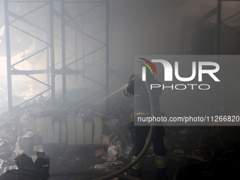 A firefighter is pouring water during a response effort to a Russian S-300 missile strike on a printing company in Kharkiv, Ukraine, on May...