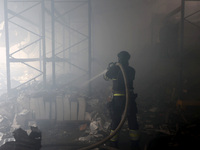 A firefighter is pouring water during a response effort to a Russian S-300 missile strike on a printing company in Kharkiv, Ukraine, on May...