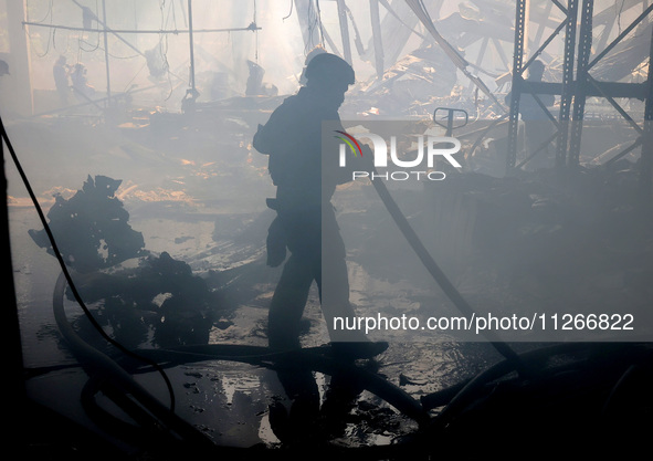 A firefighter is putting out a fire during a response effort to a Russian S-300 missile strike on a printing company in Kharkiv, Ukraine, on...