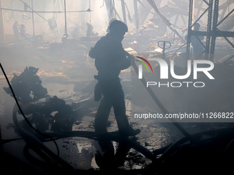 A firefighter is putting out a fire during a response effort to a Russian S-300 missile strike on a printing company in Kharkiv, Ukraine, on...