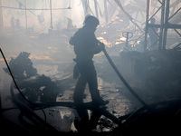 A firefighter is putting out a fire during a response effort to a Russian S-300 missile strike on a printing company in Kharkiv, Ukraine, on...