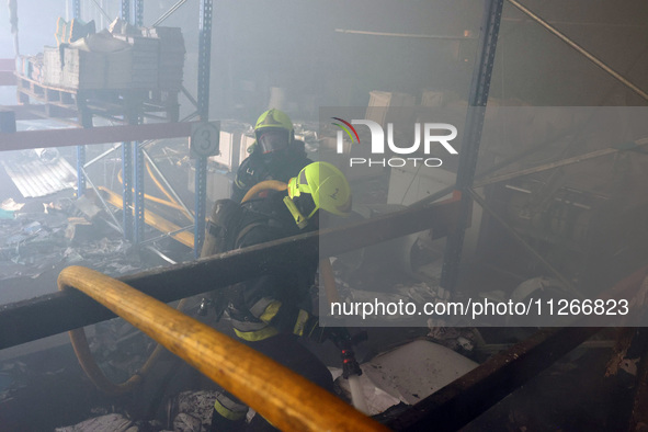 Firefighters are putting out a fire during a response effort to a Russian S-300 missile strike on a printing company in Kharkiv, Ukraine, on...