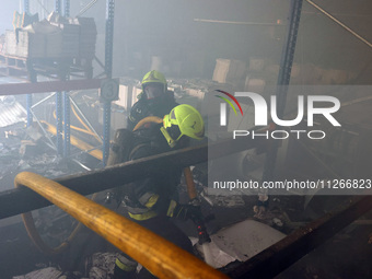 Firefighters are putting out a fire during a response effort to a Russian S-300 missile strike on a printing company in Kharkiv, Ukraine, on...