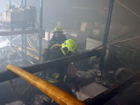 Firefighters are putting out a fire during a response effort to a Russian S-300 missile strike on a printing company in Kharkiv, Ukraine, on...