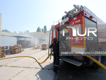 A firefighter is manning a fire engine during a response effort to a Russian S-300 missile strike on a printing company in Kharkiv, Ukraine,...