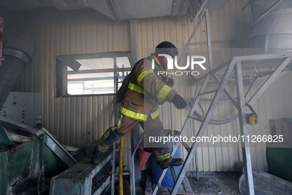 A firefighter is jumping onto a ladder during a response effort to a Russian S-300 missile strike on a printing company in Kharkiv, Ukraine,...