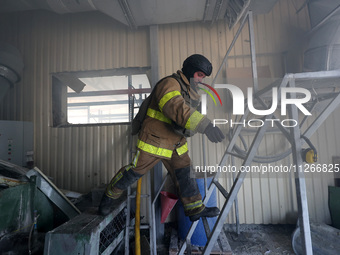 A firefighter is jumping onto a ladder during a response effort to a Russian S-300 missile strike on a printing company in Kharkiv, Ukraine,...