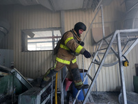 A firefighter is jumping onto a ladder during a response effort to a Russian S-300 missile strike on a printing company in Kharkiv, Ukraine,...