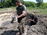 Forensic experts are working at the crater of a projectile during a response effort to a Russian S-300 missile strike on a printing company...