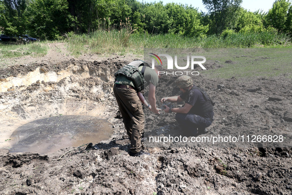 Forensic experts are working at the crater of a projectile during a response effort to a Russian S-300 missile strike on a printing company...