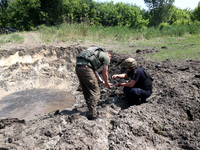 Forensic experts are working at the crater of a projectile during a response effort to a Russian S-300 missile strike on a printing company...