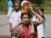 A Tamil Hindu woman is carrying a pot on her head filled with milk and honey, with a facial skewer, as devotees are taking part in the chari...