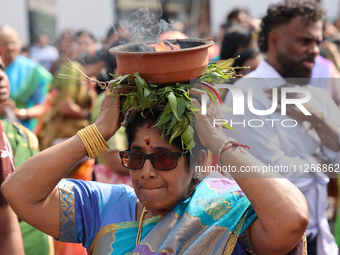 A woman is carrying a clay pot with flaming camphor on her head as Tamil Hindu devotees are taking part in the chariot procession (ther) dur...