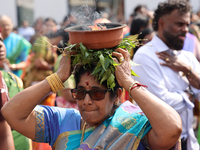 A woman is carrying a clay pot with flaming camphor on her head as Tamil Hindu devotees are taking part in the chariot procession (ther) dur...