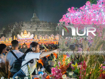 Devotees are using umbrellas for shelter during the Vesak celebration at Borobudur Temple. Despite the rainfall, their spirits are remaining...