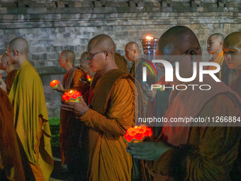 Monks are performing the Pindapata ritual, carrying lotus lamps and circling Borobudur Temple three times. (