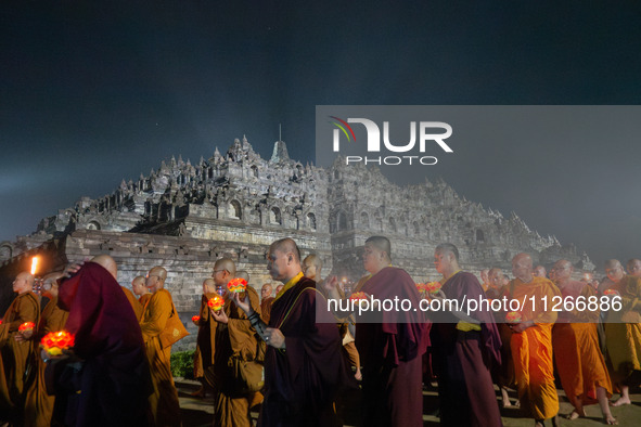 Monks are performing the Pindapata ritual, carrying lotus lamps and circling Borobudur Temple three times. 