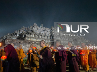 Monks are performing the Pindapata ritual, carrying lotus lamps and circling Borobudur Temple three times. (