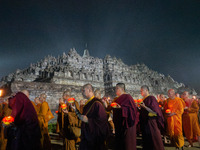 Monks are performing the Pindapata ritual, carrying lotus lamps and circling Borobudur Temple three times. (