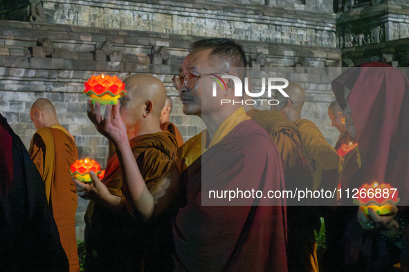 Monks are performing the Pindapata ritual, carrying lotus lamps and circling Borobudur Temple three times. 