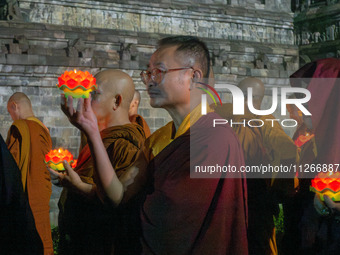 Monks are performing the Pindapata ritual, carrying lotus lamps and circling Borobudur Temple three times. (