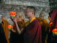 Monks are performing the Pindapata ritual, carrying lotus lamps and circling Borobudur Temple three times. (