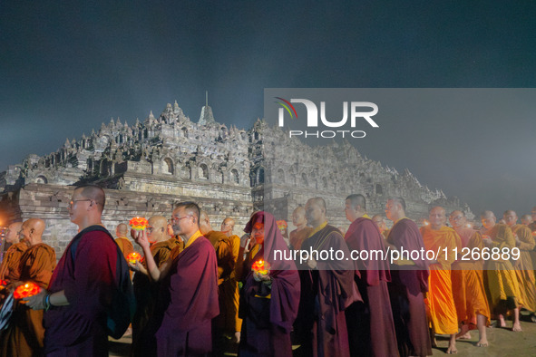 Monks are performing the Pindapata ritual, carrying lotus lamps and circling Borobudur Temple three times. 