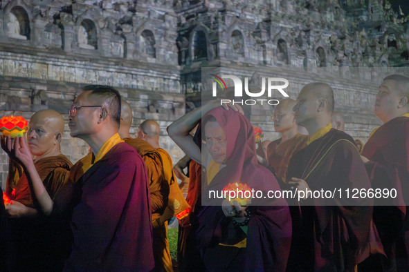 Monks are performing the Pindapata ritual, carrying lotus lamps and circling Borobudur Temple three times. 