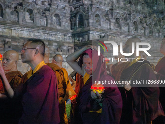 Monks are performing the Pindapata ritual, carrying lotus lamps and circling Borobudur Temple three times. (