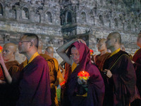 Monks are performing the Pindapata ritual, carrying lotus lamps and circling Borobudur Temple three times. (