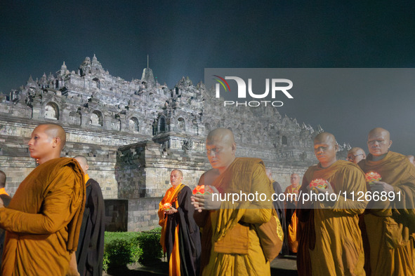 Monks are performing the Pindapata ritual, carrying lotus lamps and circling Borobudur Temple three times. 