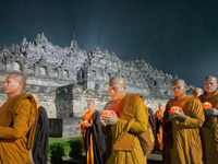 Monks are performing the Pindapata ritual, carrying lotus lamps and circling Borobudur Temple three times. (