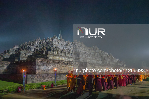 Monks are performing the Pindapata ritual, carrying lotus lamps and circling Borobudur Temple three times. 