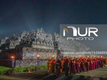 Monks are performing the Pindapata ritual, carrying lotus lamps and circling Borobudur Temple three times. (