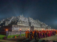 Monks are performing the Pindapata ritual, carrying lotus lamps and circling Borobudur Temple three times. (