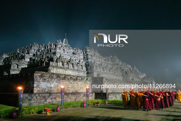 Monks are performing the Pindapata ritual, carrying lotus lamps and circling Borobudur Temple three times. 