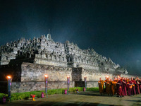 Monks are performing the Pindapata ritual, carrying lotus lamps and circling Borobudur Temple three times. (