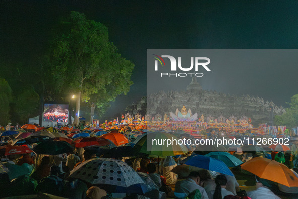 Devotees are using umbrellas for shelter during the Vesak celebration at Borobudur Temple. Despite the rainfall, their spirits are remaining...