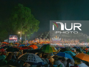 Devotees are using umbrellas for shelter during the Vesak celebration at Borobudur Temple. Despite the rainfall, their spirits are remaining...