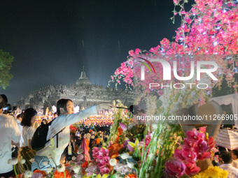 Devotees are bathing the statue of baby Siddhartha Gautama during the Vesak celebration. This ritual is signifying purification and the birt...