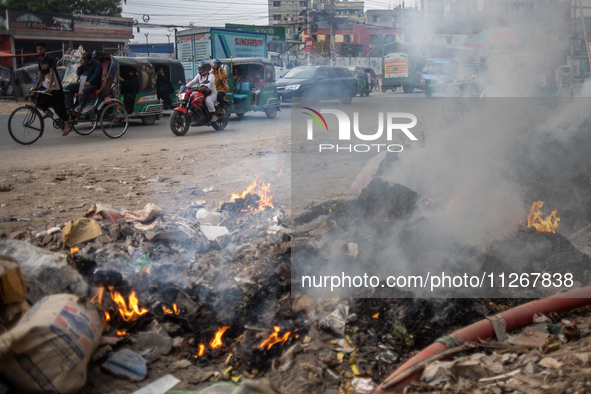 People are moving past burning garbage and plastic trash beside a busy road in Dhaka, Bangladesh, on May 23, 2024. Dhaka's air quality is be...